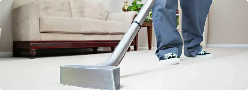Carpet cleaning technician using a hot-water extraction wand on a light-colored carpet in a living room, Philadelphia, PA.