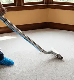 Steam carpet cleaning technician using a hot-water extraction wand on a residential carpet, wearing blue protective shoe covers Philadelphia, PA.