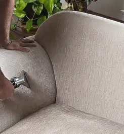 Professional upholstery cleaner deep-cleaning a fabric sofa with a handheld extraction tool and hose Philadelphia, PA.